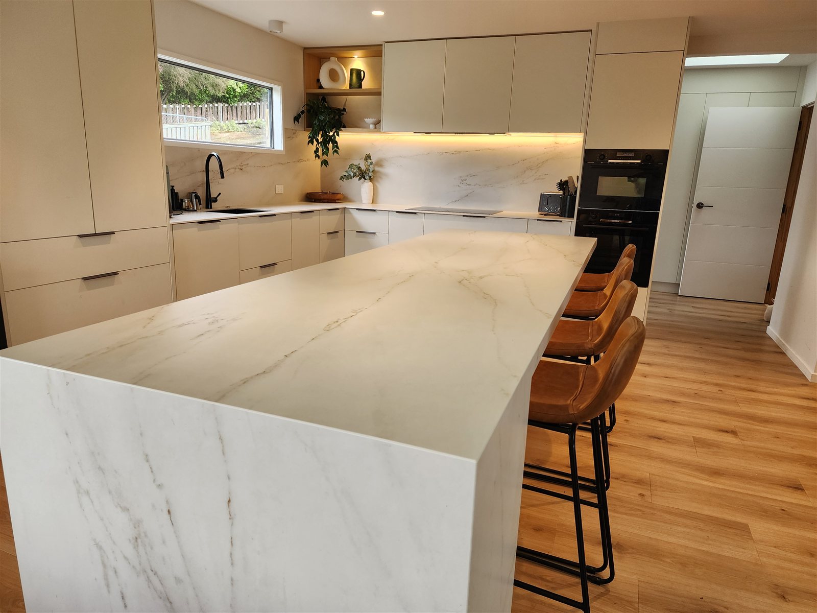 Open-plan kitchen with waterfall marble island and pendant lighting