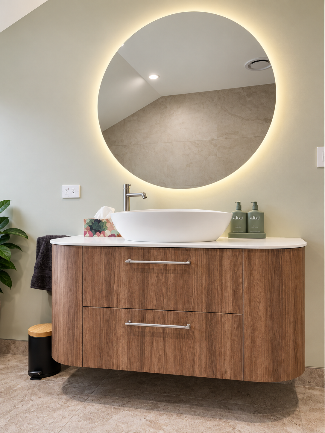 Walnut floating vanity with vessel sink, white stone benchtop and large round LED-backlit mirror